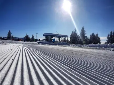 a snow covered road with the sun in the background at Apartman Brvenik 103, Konaci, Kopaonik in Kopaonik