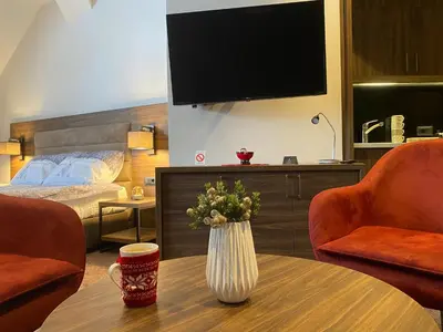 a hotel room with a table with a vase of flowers on it at Teddy Apartman Kula Konaci in Kopaonik