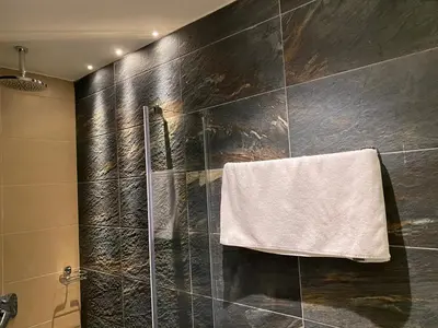 a bathroom with a shower with a towel hanging on the wall at Teddy Apartman Kula Konaci in Kopaonik