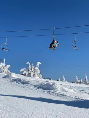 a person riding a snowboard under a ski lift at Teddy Apartman Kula Konaci in Kopaonik