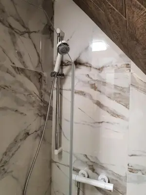 a shower in a bathroom with a marble wall at VT apartman-KOZNIK in Kopaonik