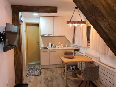 a small kitchen with a wooden table and a dining room at VT apartman-KOZNIK in Kopaonik