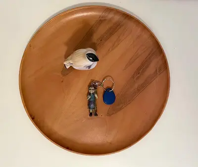 a small toy figure in a wooden bowl with a keychain at Alva Apartment in Niš