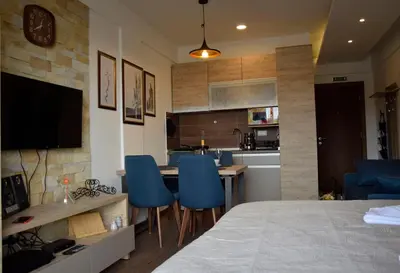 a room with a bed and a kitchen with blue chairs at DA-MA Milmari in Kopaonik