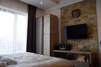 a bedroom with a bed and a tv on a stone wall at DA-MA Milmari in Kopaonik