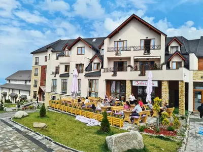 a hotel with people sitting at tables in front of it at DA-MA Milmari in Kopaonik