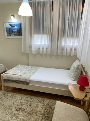 a bed sitting in a room with a window at Apartmani Jelica FREE PARKING in Vranje