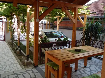 a wooden pergola with a table and a car parked at Apartmani Jelica FREE PARKING in Vranje