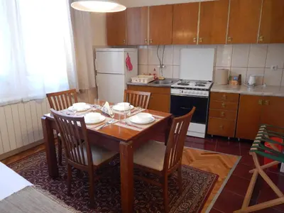 a kitchen with a wooden table and chairs and a kitchen with a refrigerator at Apartmani Jelica FREE PARKING in Vranje