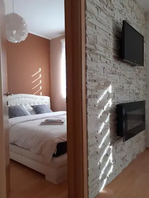 a bedroom with a stone wall with a bed and a tv at Apartman Teodora in Kopaonik