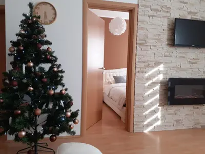 a christmas tree in a living room with a mirror at Apartman Teodora in Kopaonik