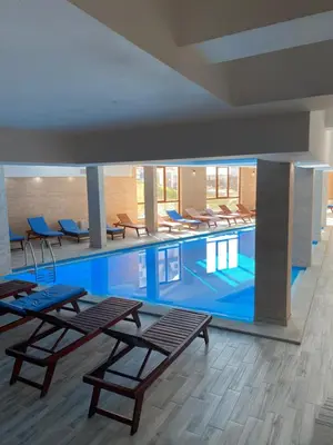 a large swimming pool with tables and chairs in a building at FamilyKop Apartments Milmari in Kopaonik