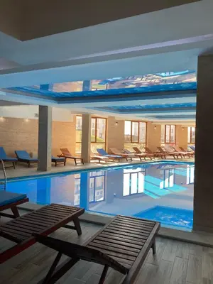 a large swimming pool with tables and chairs in a building at FamilyKop Apartments Milmari in Kopaonik