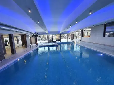 a large swimming pool with blue water in a building at Apartman Žuta dunja - Sunčani breg in Kopaonik