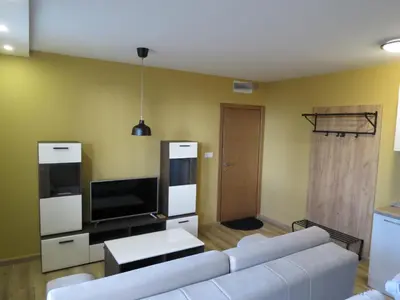 a living room with a white couch and a tv at Apartman Žuta dunja - Sunčani breg in Kopaonik