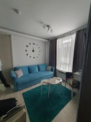a living room with a blue couch and a clock on the wall at Milmari apartman SAN-28 in Kopaonik