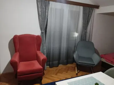a living room with a red chair and two chairs at Apartmani Marić in Vrnjacka Banja in Vrnjačka Banja