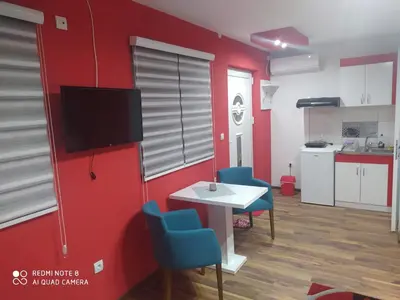 a living room with a red wall and a table and chairs at Apartmani Marić in Vrnjacka Banja in Vrnjačka Banja