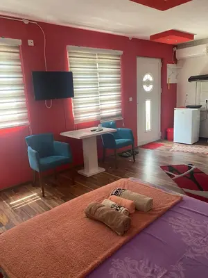 a living room with red walls and a table and chairs at Apartmani Marić in Vrnjacka Banja in Vrnjačka Banja