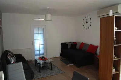 a living room with a couch and a clock on the wall at Stan na dan - apartman Djordjevic in Vranje