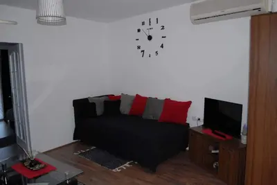 a living room with a couch and a clock on the wall at Stan na dan - apartman Djordjevic in Vranje