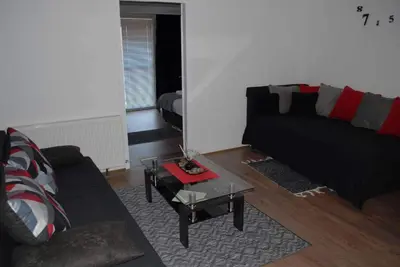 a living room with a black couch and a table at Stan na dan - apartman Djordjevic in Vranje