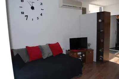 a living room with a couch and a clock on the wall at Stan na dan - apartman Djordjevic in Vranje