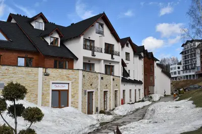 a white house with a black roof in the snow at S 68, Milmari Resort in Kopaonik
