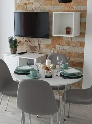 a white table with chairs and a tv on a wall at Apartment Mali Princ S18 Milmari resort in Kopaonik