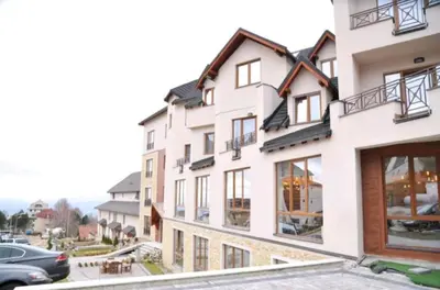 a large white building with windows and a parking lot at Andre P05 Milmari in Kopaonik