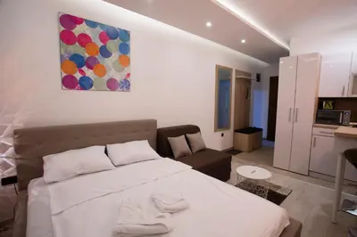 a bedroom with a bed and a couch and a painting at Dream Lux Apartman Kopaonik in Kopaonik