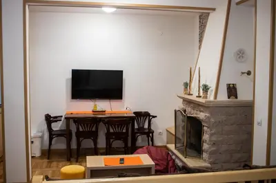 a living room with a television and a table with chairs at Apartman sa kaminom Vila Mina in Kopaonik