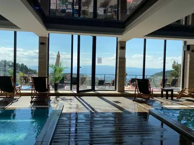 a swimming pool with chairs and a view of the water at Ski & Spa Apartment S20 Milmari Resort Kopaonik in Kopaonik