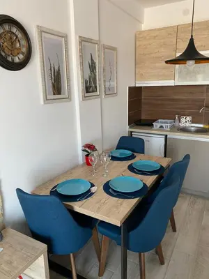 a dining room table with blue chairs and a kitchen at Mount Apartments Milmari in Kopaonik