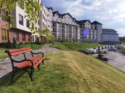 a park bench sitting in the grass in front of a building at Milmari-Apartman MARA L30 in Kopaonik