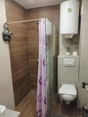 a bathroom with a shower curtain and a toilet at Milmari-Apartman MARA L30 in Kopaonik