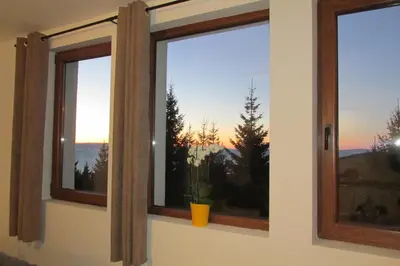 two windows in a room with a view of the sunset at JOPA Suncani breg in Kopaonik