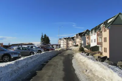 a snowy street with cars parked in a parking lot at JOPA Suncani breg in Kopaonik