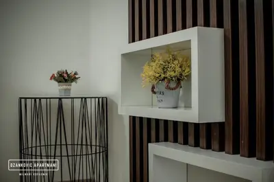 a white shelf with flowers on a wall at Apartmani Džanković in Kopaonik