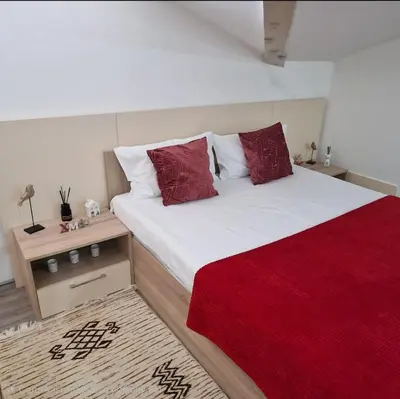 a bedroom with a large bed with red pillows at Square Apartment in Paraćin