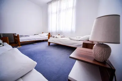 a room with three beds and a lamp on a table at Apartman Lux in Pirot