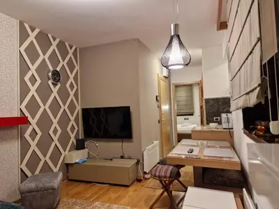 a living room with a table and a tv on a wall at Vila Pahulja A3 in Kopaonik