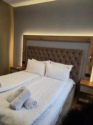a bed with white sheets and a stuffed animal on it at Vila Pahulja A3 in Kopaonik
