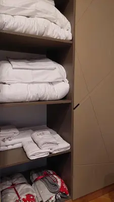 a closet filled with white towels and a bed at Vila Pahulja A3 in Kopaonik