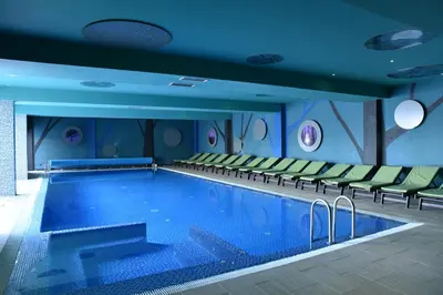 a large swimming pool in a hotel room with chairs at Private apartman 5b23 in Kraljevi cardaci in Kopaonik