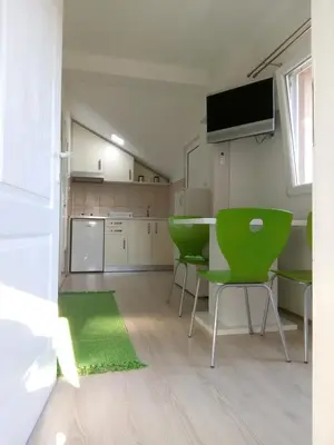 a living room with a table and green chairs at Smeštaj Milenković in Soko Banja