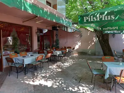 a restaurant with tables and chairs and a green umbrella at Šumatovac in Aleksinac