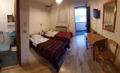 a room with two beds and a table and a desk at Šumatovac in Aleksinac
