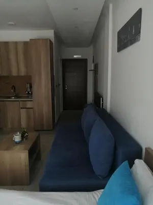 a living room with a blue couch and a kitchen at Apartman Adelfes P16, Milmari Resort in Kopaonik