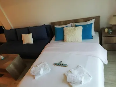 a large white bed with blue pillows and a couch at Apartman Adelfes P16, Milmari Resort in Kopaonik